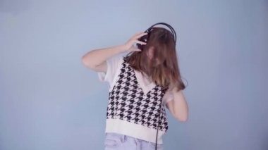Ekose giysili hoş bir Avrupalı genç kız dans ediyor ve müzik dinliyor.