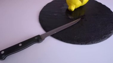 Bir mutfak bıçağı ve boyalı gözlü bir limon kesme tahtasının üzerinde yatıyor.