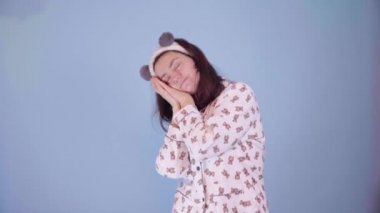 Panda kulaklı, pijama giymiş beyaz bir kadın komik bir şekilde dans ediyor.