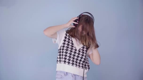 Une jolie adolescente européenne vêtue d'un gilet à carreaux à la mode et un jean bleu danse et écoute de la musique — Video