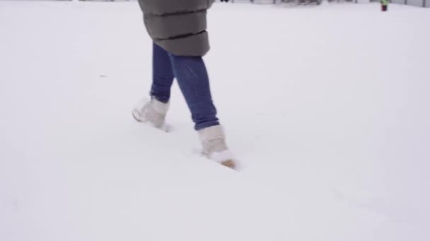 Le ragazze piedi in stivali e jeans passo sulla neve. vicino, piedi che camminano sulla neve bianca — Video Stock