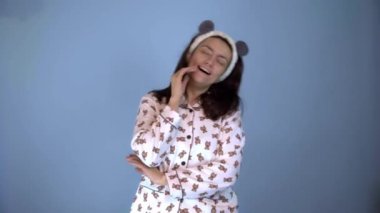 Panda kulaklı, pijama giymiş beyaz bir kadın komik bir şekilde dans ediyor.