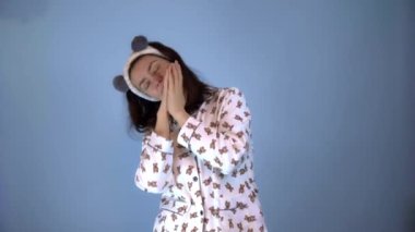 Panda kulaklı, pijama giymiş beyaz bir kadın komik bir şekilde dans ediyor.