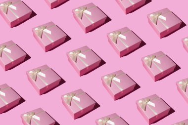 Pastel pembe arka planda pembe hediye kutusu deseni. Düz yerde, üst tarafta. Kış tatili fikri. Asgari Noel ve Yeni Yıl kutlamaları konsepti. 