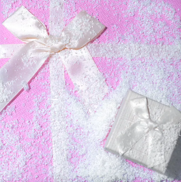 Pastel pembe kutunun üstünde küçük bej renkli hediye kutusu var. Kurdeleli, karla kaplı. En az yeni yıl ve kış tatili konsepti. Kopyalama alanı ile.