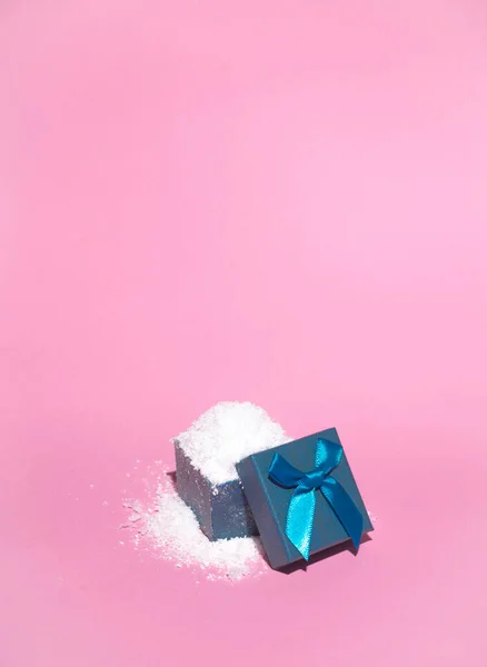 Pastel pembe arka planda kar dolu mavi hediye kutusu. Kış tatili fikri. Minimum Noel ve Yeni Yıl konsepti. Kopyalama alanı ile.