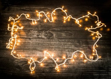 Yaratıcı kış tatili planı. Noel ağacı ışıkları koyu ahşap tahtaları çerçeveliyor. Düz yerde, üst tarafta. Minimum Yeni Yıl ve Noel konsepti. Boşluğu kopyala.