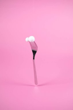 Pastel pembe arka planda kartopları olan çatal. Noel ve Yeni Yıl fikri. Asgari kış tatili konsepti. 