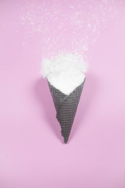 Pastel arka planda kar dolu dondurma külahı. Düz yerde, üst tarafta. Yeni yıl ve Noel fikri. Kış tatili konsepti asgari düzeyde. Boşluğu kopyala.