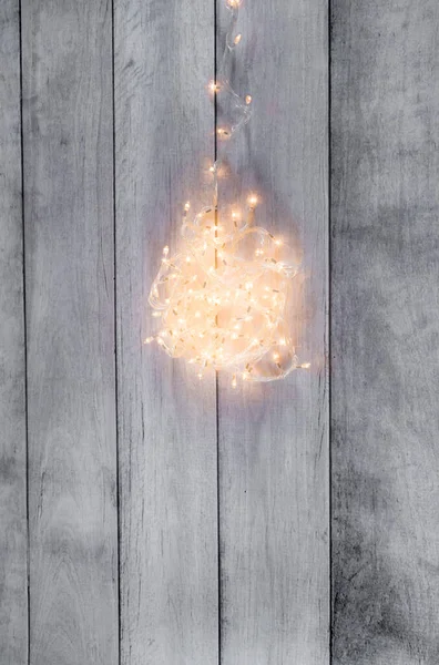 Yaratıcı kış tatili planı. Noel ağacı ışıkları gri ahşap tahtalarda avize oluşturuyor. Düz yerde, üst tarafta. Minimum Yeni Yıl ve Noel konsepti. Boşluğu kopyala.