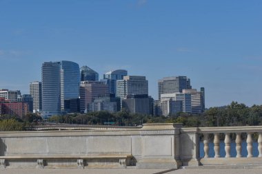 Arlington, Virginia, ABD - 25 Ekim 2021: Arlington Skyline as see from the Memorial Bridge on a Sunny Fall Afternoon with Bridges Beton Trabzan ve A Bench in the Fronground