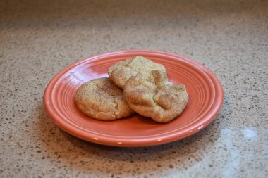 Turuncu bir tabakta ev yapımı üç kurabiye yakın plan.