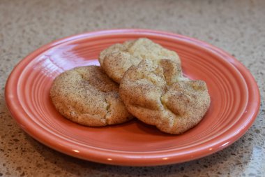 Turuncu bir tabakta ev yapımı üç kurabiye yakın plan.