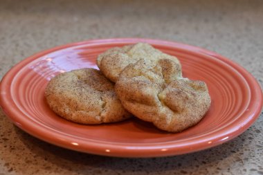 Turuncu bir tabakta ev yapımı üç kurabiye yakın plan.