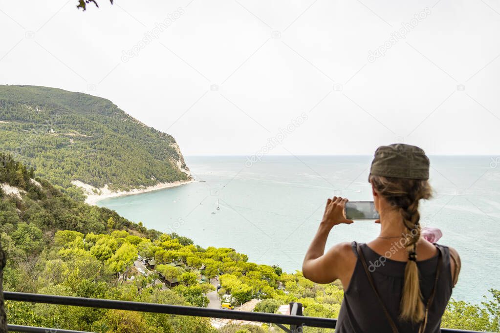 Girl photographing the sea from Sirolo, Marche - Italy