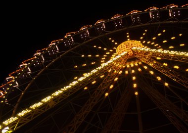 Sarı neon ışıklı dönme dolap açılı karanlık gece arkaplanı.