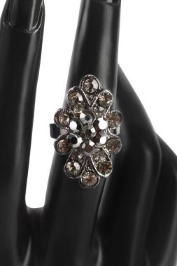 Çiçek şeklinde parlak elmaslarla süslü gümüş bir yüzük. Manken elinde. Yaklaş. Moda mücevherleri..