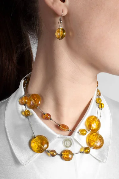 Amber jewelry set on the girl: necklace with amber stones and earrings. Fashion bijouterie.