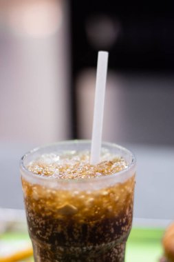 A close up picture of coke with ice and straw in a glass