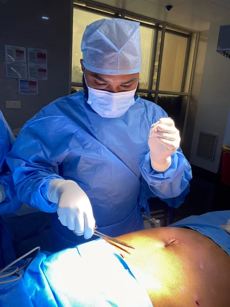 A picture of a Indian doctor doing suturing after the surgery in an operation theater