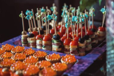 Kırmızı havyarlı turta ve mor tepside kırmızı balık sosis, salatalık, domates ve peynirin yanında.