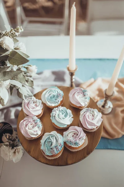 Blå Och Rosa Cupcakes Träbricka Mot Bakgrund Ljusstakar Vita Blommor — Stockfoto