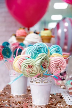 Bir çubuğun üzerinde çok renkli krema, bulanık bir arka planda çok renkli boncuklarla süslenmiş.