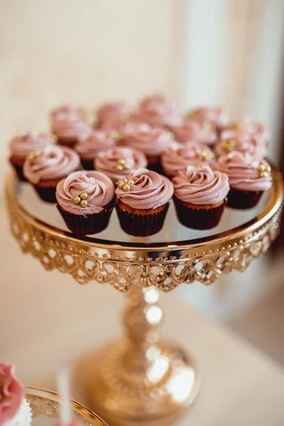 베이지 배경에 황금색 쟁반에 분홍색 크림이 과자로 장식된 컵케이크 — 스톡 사진