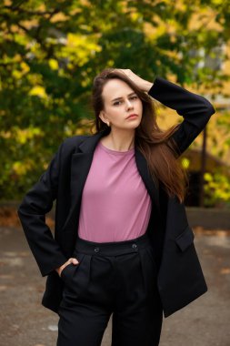 Parkın arka planında siyah pantolonlu ve pembe tişörtlü genç bir kadın var.