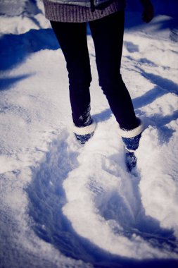Siyah taytlı, beyaz kürklü, kışlık çizmeli bir kız.