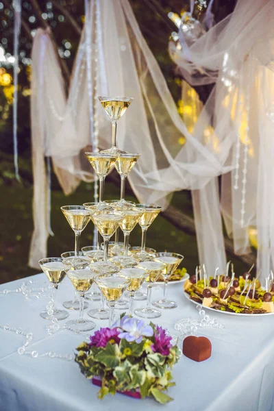 新娘用紫丁香兰花和紫色的花束 在婚纱装饰的背景下 用香槟酒金字塔装饰婚戒 — 图库照片
