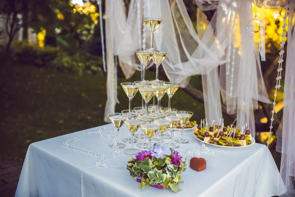 新娘用紫丁香兰花和紫色的花束 在婚纱装饰的背景下 用香槟酒金字塔装饰婚戒 — 图库照片