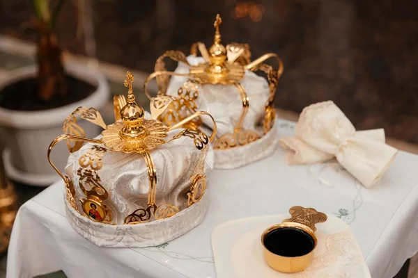 金冠上的白色面料图案躺在一个桌子上 旁边的金杯盛满了酒 象征着人生的欢乐与悲伤 — 图库照片