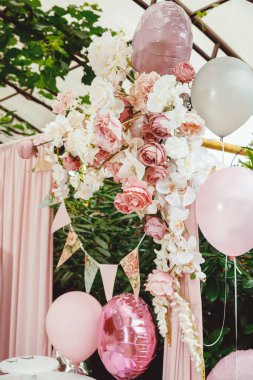 Yeşil arka planda gül desenli bayrak kurdelesi, pembe perde ve doğum günü fotoğrafının bir parçası olarak çiçek aranjmanı.