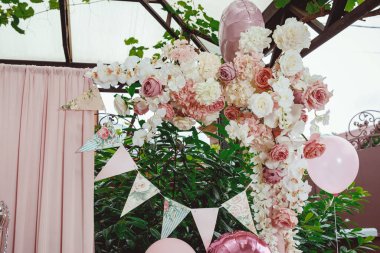 Yeşil arka planda gül desenli bayrak kurdelesi, pembe perde ve doğum günü fotoğrafının bir parçası olarak çiçek aranjmanı.