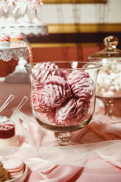 粉红的棉花糖放在透明的罐子里 在纸杯蛋糕的背景上撒上糖粉 小棉花糖放在模糊的罐子里 — 图库照片