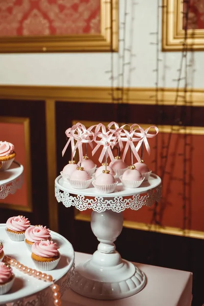 用粉红奶油和金黄色糕点装饰在模糊米色背景的白色托盘上的流行蛋糕 — 图库照片