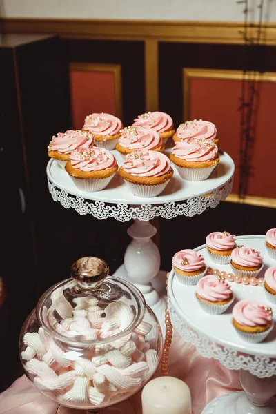 粉红奶油纸杯蛋糕 白色盘子上装饰着金黄色的糕点 底色模糊 — 图库照片