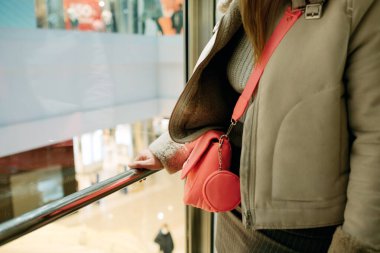 Asansör, alışveriş merkezinin asansöründe parmaklıklara dokunan genç bir kadın omzunda pembe çantasıyla asansör parmaklıklarına tutunan bir kadın, yüksek katlı alışveriş merkezleri.