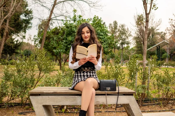 Διαβάζοντας Νεαρή Γυναίκα Κάθεται Στο Παγκάκι Του Πάρκου Κατά Διάρκεια — Φωτογραφία Αρχείου