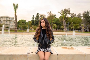 Stresli bir bekleyiş içinde genç bir kadın, depresyonda ve bir havuz kenarında oturuyor, depresyon ve endişe bozukluğu var.