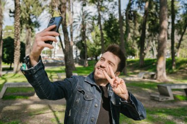 Selfie, kot ceketli yakışıklı adam selfie çekiyor, mutlu bir gülümseme ve sosyal medyada paylaşılacak güzel bir poz.