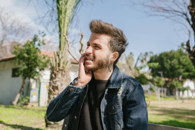 Diş ağrısı, çenesini ağrıyan dişin önünde tutan genç bir adam dişçiden korkan genç bir yetişkin.