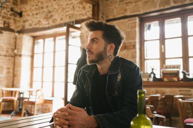 Bir kafede oturan ve gözlerini kaçıran yakışıklı bir delikanlının yakın çekimi. Önemli haberleri bekliyor..