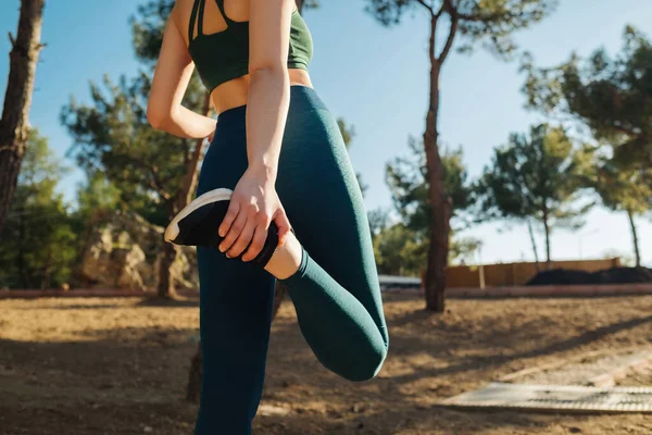 Young fitness woman wearing yoga pant and sports bra runner stretching legs before run on city park outdoor. Fitness and workout wellness, start straight concept of challenge or career path and change