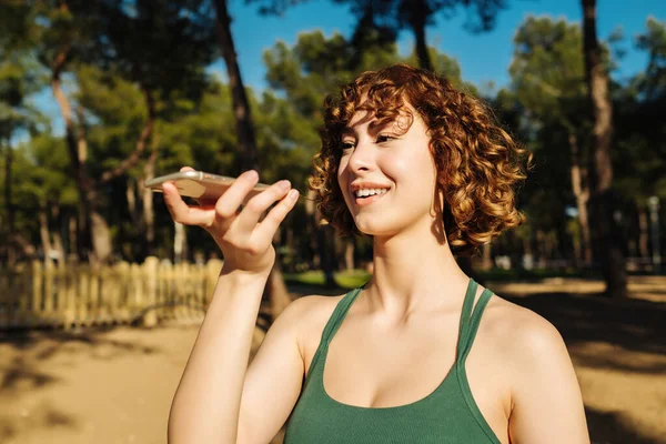 Cep telefonu ya da dijital yardım uygulaması kullanarak telefonu tutan mutlu genç kızıl saçlı kadın sanal asistanı, kayıt mesajını ya da akıllı telefondan konuşmayı etkinleştir.