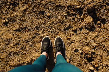 Siyah spor ayakkabılı kadın bacakları ve şehir parkında üzerinde fotokopi alanı olan mavi yoga pantolonları. Üst bakış açısı ve kişisel bakış açısı.
