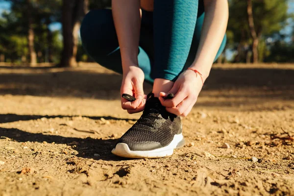 Sportive woman wear running shoe on to walking and running on nature green background. Tying jogging shoes, health exercise and outdoor sport concepts.