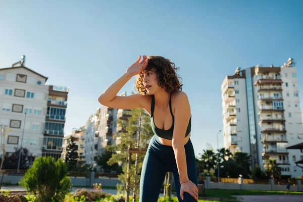 Kadın sporcu antrenmandan sonra yorgun görünüyor. Yoğun fiziksel eğitimden sonra yorgun düşmüş bir kadın. Açık hava sporları ve sağlıklı yaşam tarzı kavramları.