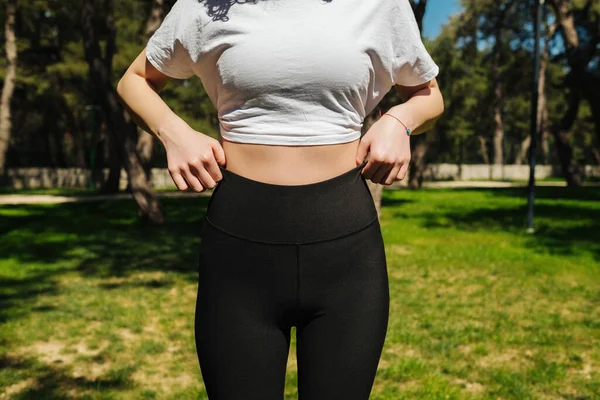 Молодая Женщина Белой Футболке Черных Штанах Йоги Показывающих Тонированное Тело — стоковое фото